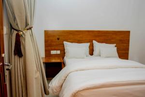 Schlafzimmer mit einem großen Bett mit einem Kopfteil aus Holz in der Unterkunft ALLY NGALI MOTEL in Kigali