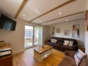 a living room with a couch and a table at Folly Cottage & The Old Forge in Colerne
