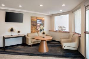皇后區的住宿－紐約拉瓜迪亞機場/芙拉世迎費爾菲爾德萬豪酒店，一间设有椅子和桌子的等候室以及一台电视