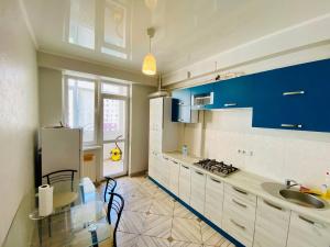 een keuken met blauwe kasten, een tafel en een wastafel bij Voyage 2 ROOMS Apartment in Chişinău
