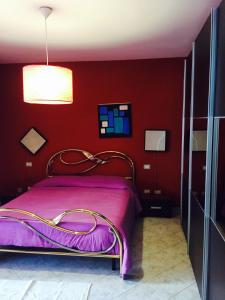 クアルトゥ・サンテーレナにあるAtene Apartmentの赤い壁の紫色のベッドが備わるベッドルーム1室が備わります。