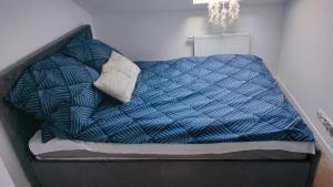 a bed with a blue comforter and two pillows at Apartament z pięknym widokiem in Nowy Dwór Mazowiecki