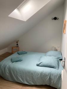 a white bedroom with a bed with blue pillows at Rive droite bord de plage in Réville