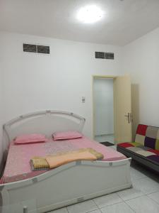 a bedroom with a bed with pink sheets and a chair at Holiday Home 2 Bedrooms Apartment for Family Only in Sharjah
