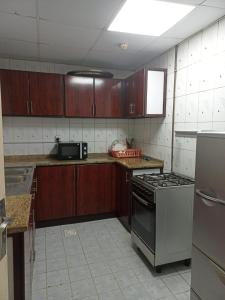 een keuken met houten kasten en een fornuis met oven bij Holiday Home 2 Bedrooms Apartment for Family Only in Sharjah