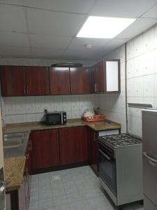 cocina con armarios de madera y horno con fogones en Holiday Home 2 Bedrooms Apartment for Family Only, en Sharjah