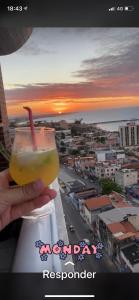 una persona sosteniendo una bebida con vistas a una ciudad en Apartamento Iracema Fortaleza en Fortaleza