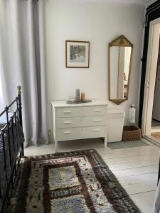a bedroom with a white dresser and a mirror at Kostastugan in Kosta