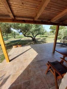 a patio with a wooden roof and a table and chairs at Robinson house Sea & olives in Tisno