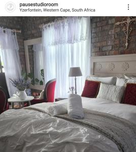 Pause Studio Room Yzerfontein في يزرفونتين: غرفة نوم بسرير ابيض كبير مع ستائر بيضاء