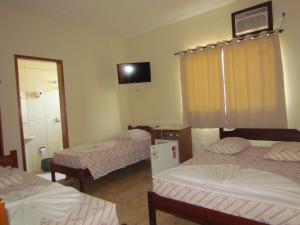 a room with three beds and a tv in it at Hotel Colorado in Aparecida