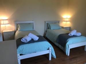 a bedroom with two beds with towels on them at Harsgeir View Holiday Cottage -Wifi Go green in Breaclete
