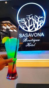 una persona che tiene un drink colorato in un bicchiere di Sasavona Boutique Hotel a Polokwane