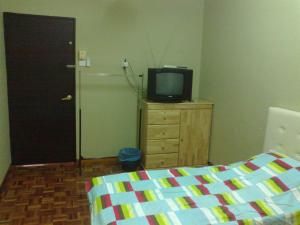Dormitorio con cama y tocador con TV en Pan Homestay, en Kuantan