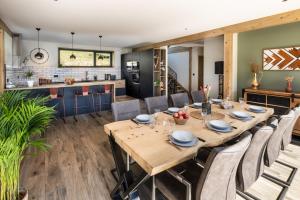 uma sala de jantar e cozinha com mesa e cadeiras de madeira em Chalet neuf, piscine privée, Jacuzzi, pétanque em Aime La Plagne