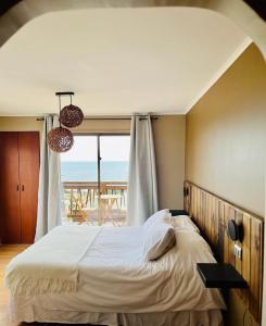een slaapkamer met een bed en uitzicht op de oceaan bij Blumen Hotel in Concón