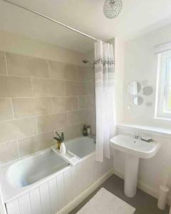 une salle de bain blanche avec une baignoire et un lavabo dans l'établissement Beautiful, cosy home in Connel, 5 mile drive from Oban, à Connel