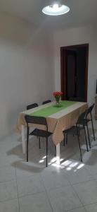 einen Tisch mit Stühlen und eine Vase mit Blumen darauf in der Unterkunft Casa vacanze Il Portoncino in Ercolano