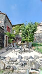 a patio with a table and chairs and a stone wall at Le Carpé Diem in Saint-Privat-dʼAllier