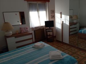 a bedroom with a bed and a tv and a mirror at Casa vacanze Il Carrubo in Leporano