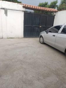 Srebrny samochód zaparkowany przed garażem w obiekcie Hospedaje Doña Victoria w mieście Santa Marta