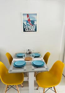 uma mesa de jantar com cadeiras amarelas e pratos azuis em Le 18B em La Pironnière