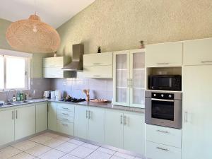 a white kitchen with white cabinets and a microwave at Azur - Résidence Le Dattier in Flic-en-Flac