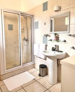a white bathroom with a shower and a sink at Azur - Résidence Le Dattier in Flic-en-Flac