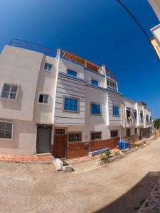 a large white building with blue windows on a street at Seaside House in Imsouane