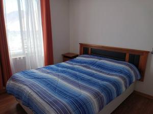 a bedroom with a bed with a blue comforter and a window at Luminoso depto 3 dormitorios 2 baños frente al mar in Iquique