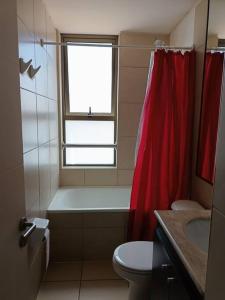 y baño con aseo y cortina de ducha roja. en Luminoso depto 3 dormitorios 2 baños frente al mar en Iquique