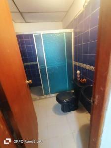 baño con aseo negro y pared de azulejos azules en Hospedaje Doña Victoria, en Santa Marta