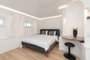a white bedroom with a bed and a table at Hilltop Apartments - City Centre in Tallinn