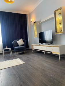 uma sala de estar com uma televisão de ecrã plano e uma cadeira em New luxury and quiet apartmant em Istambul