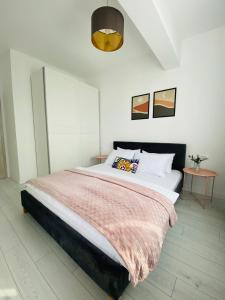 a bedroom with a large bed with a pink blanket at Orhideea Central Apartments in Bucharest