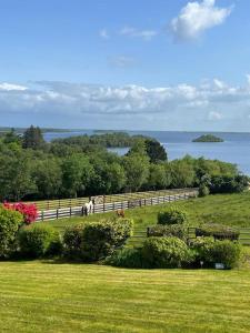 un campo con una valla y vistas al agua en Hillcrest Lodge, Private apartment on Lough Corrib, Oughterard, en Galway