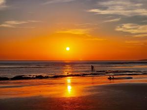 eine Person, die bei Sonnenuntergang am Strand spazieren geht in der Unterkunft Surf House Desert Point in Tiguert