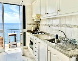 ポンタ・ド・ソルにあるApartment Paulo by Your Madeira Rentalsの白いキッチン(海の景色を望む)