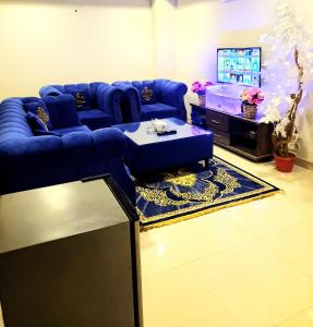 sala de estar con sofá azul y TV en Anabi Apartments and Suits E11 Islamabad en Islamabad