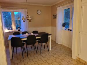 Mysigt hus utanför Järvsö في يارفسو: طاولة غرفة طعام مع كراسي سوداء وساعة على الحائط