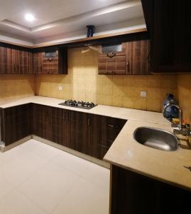 una cocina con armarios de madera y fregadero en Anabi Apartments and Suits E11 Islamabad en Islamabad