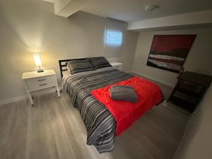 um quarto com uma cama com um cobertor vermelho em Comfy 2 Bedroom Near The Beach! em Pickering