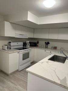 uma cozinha com armários brancos e um forno com placa de fogão em Comfy 2 Bedroom Near The Beach! em Pickering