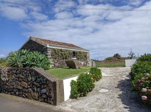 uma casa de pedra com uma parede de pedra e relva em Rosário Guest House em Lajes