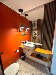pomarańczowa łazienka z umywalką i toaletą w obiekcie Residence 57 w mieście Reşiţa