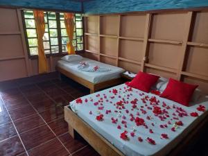 2 Betten in einem Zimmer mit roten Blumen drauf in der Unterkunft Bella Vista Corcovado in Drake
