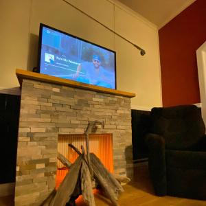 a tv on top of a stone fireplace with a fire place at Kawi Hotel in Puerto Natales