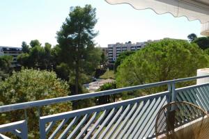 a balcony with a blue railing and trees at Standing T2 Domaine des palmiers air-conditioned with parking and pool in Cannes