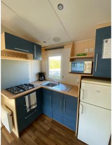 a kitchen with blue cabinets and a sink and a refrigerator at Mobile home proche de Europa Park in Boofzheim