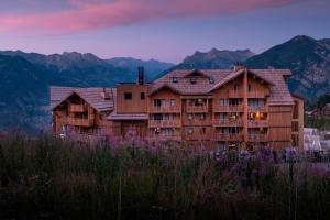 un edificio su una collina con montagne sullo sfondo di Résidence Club MMV Le Silvana a Risoul